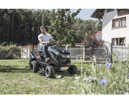 Muž jazdí na záhradnom traktore na trávniku pred domom
