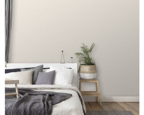 Spálňa s posteľou, vankúšmi, dekou, črepníkovou rastlinou a nočným stolíkom