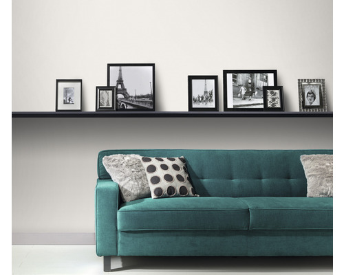 Moderná obývacia izba s tyrkysovou pohovkou, vankúšmi a radom fotorámikov na polici