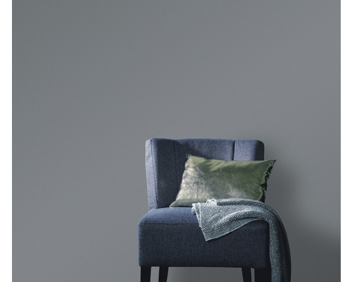 Jednofarebná tapeta za kreslom s vankúšom a dekou