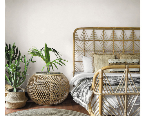 Spálňa v bohémskom štýle s bambusovou posteľou, príručným stolíkom a izbovými rastlinami