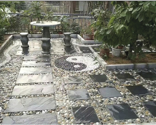 Záhradná scéna s kamenným stolom, stoličkami, chodníkovými doskami a štrkom