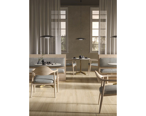 Interiérový pohľad so stolmi, stoličkami, lavicami a závesnými svietidlami v svetlej miestnosti.