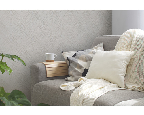 Obývacia izba so vzorovanou tapetou, pohovkou, vankúšmi a rastlinou pre útulnú atmosféru