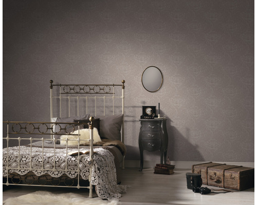 Spálňa s posteľou, nočným stolíkom a vzorovanou tapetou pre útulnú atmosféru.