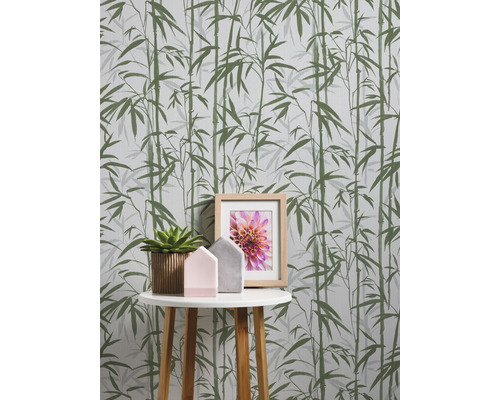 Detail steny s bambusovou tapetou, malého stolíka, izbovej rastliny, dekoračných domčekov a rámu na fotografie