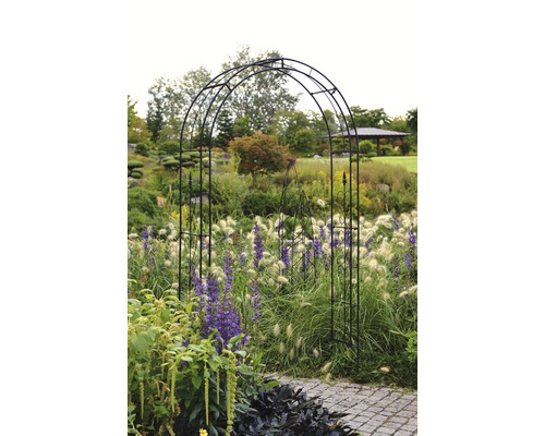 Záhradná scéna s kovovým oblúkom nad cestou.