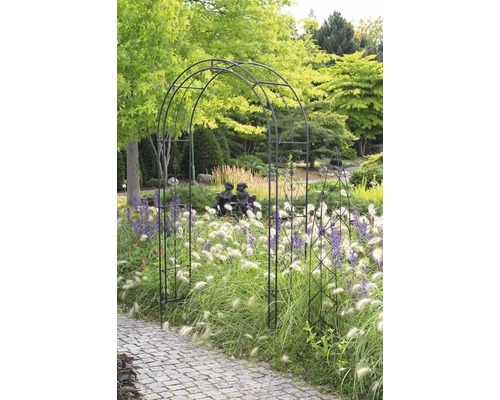 Záhradná scéna s ružovou bránou, okrasnými trávami a dláždenou cestou