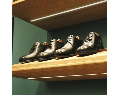 Rad čiernych kožených topánok na drevenej poličke