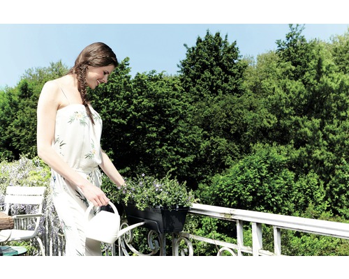 Žena zalieva kvety na balkóne s krhlou