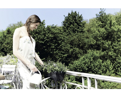 Žena polieva kvety v kvetináči kanvou.