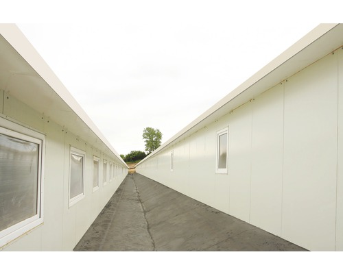 Dlhá chodba medzi dvoma radmi kancelárskych kontajnerov s oknami