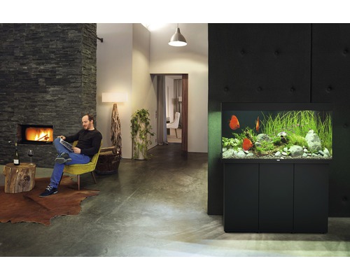Obývacia izba s akváriom, krbom a mužom čítajúcim