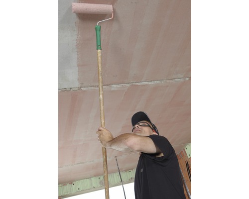 Muž natiera strop valčekom na maľovanie na tyči