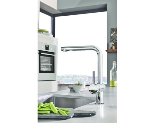 Kuchynská scéna s drezom, batériou a zeleninou na doske na krájanie