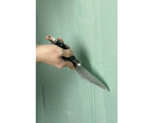 Ruka so špachtľou pri tmelení sadrokartónovej steny