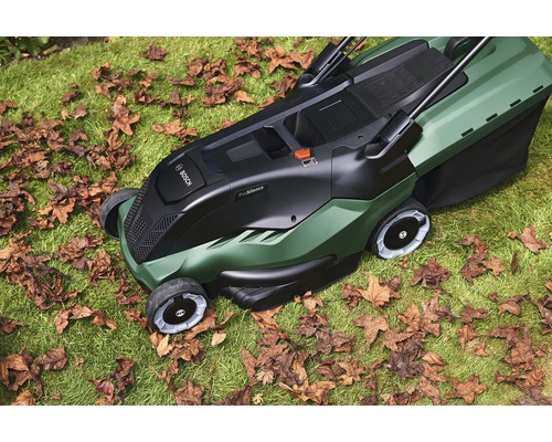 Kosačka na trávu Bosch na trávniku s jesenným lístím