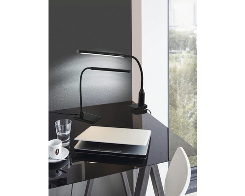 Dve čierne LED stolné lampy, jedna so základňou a jedna so svorkou, stoja na písacom stole.