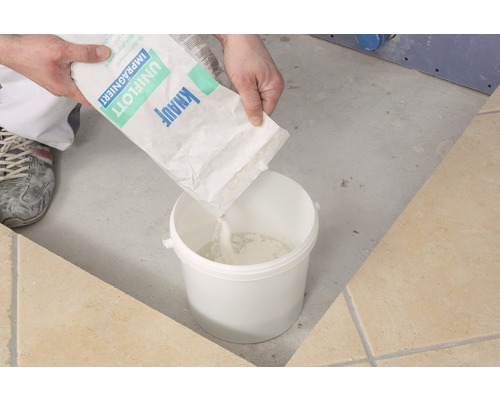 Osoba sype škárovaciu hmotu Knauf Uniflott impregnovaná do vedra