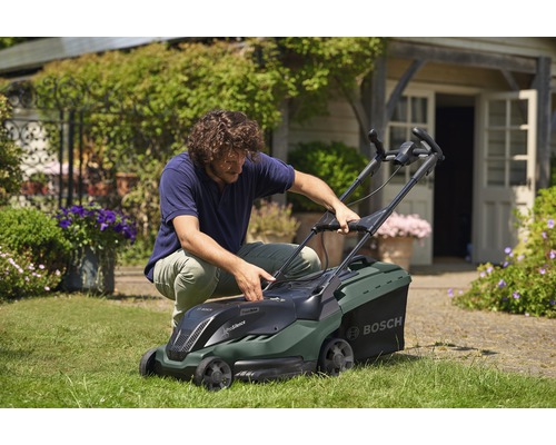 Muž pripravuje kosačku na trávu v záhrade