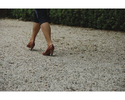 Žena kráča po štrkovej ceste v topánkach