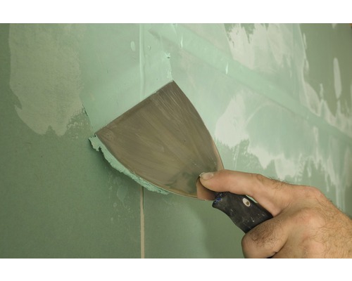 Remeselník špachtľou špachtľuje sadrokartónovú stenu