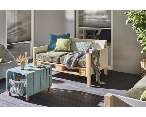 Obývacia izba s paletovým nábytkom, ktorý pozostáva z pohovky, stola a vankúšov