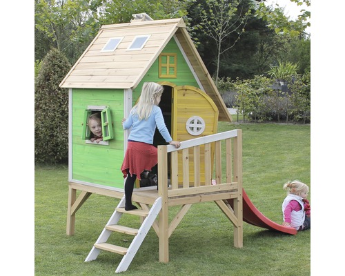 Drevený hrací domček so šmýkačkou v záhrade s hrajúcimi sa deťmi.