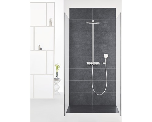 Sprchovací kabína s hlavovou a ručnou sprchou a úložným priestorom na sprchovacie potreby na tmavom obkladanom pozadí