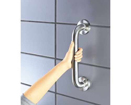 Ruka drží madlo na obloženej stene pre väčšiu bezpečnosť v kúpeľni.