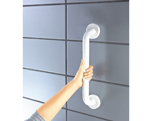 Osoba drží biele madlo na stene.