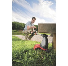 Muž používa vyžínač trávy v záhrade.