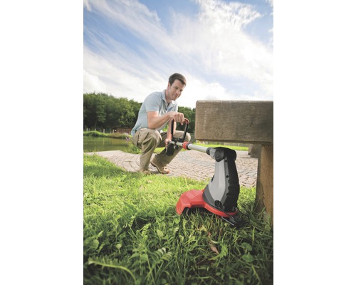 Muž používa vyžínač trávy v záhrade.