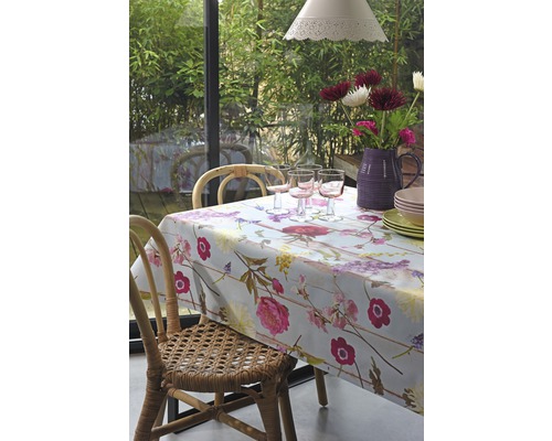 Jedálenský stôl s kvetinovým obrusom, pohármi, riadom a kvetmi vo váze