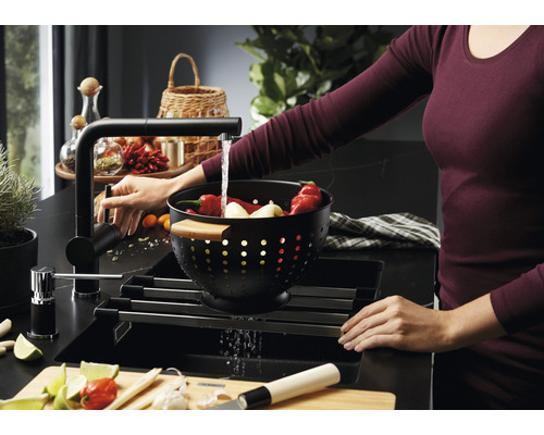 Drez s odkvapkávačom, batériou a ženou umývajúcou zeleninu