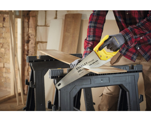 Osoba píli kus dreva na dvoch kozách ručnou pílou Stanley.