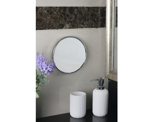 Kúpeľňová scéna s okrúhlym zrkadlom, pohárom na zubné kefky a dávkovačom mydla