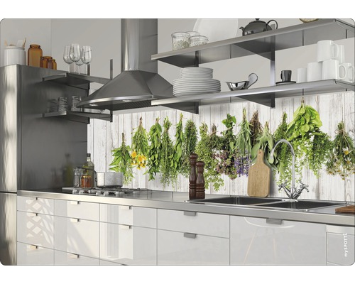 Kuchynská scéna s bielymi skrinkami, nerezovým drezom a motívom bylín na zadnej stene