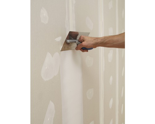 Remeselník špachtľou špachtľuje sadrokartónovú stenu.