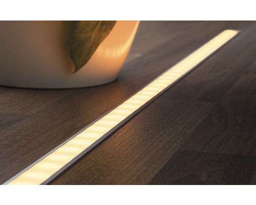 LED pásik na drevenej podlahe vedľa rastliny