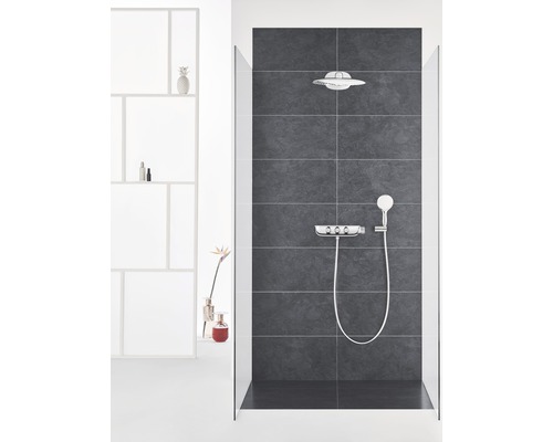 Kúpeľňa so sprchou, hlavovou sprchou, ručnou sprchou a armatúrou pred tmavým obkladom