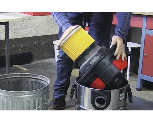 Osoba likviduje filter vysávača do odpadkového koša