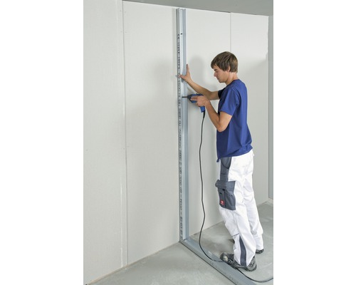 Muž pripevňuje kovový rám k vŕtačkou k stene