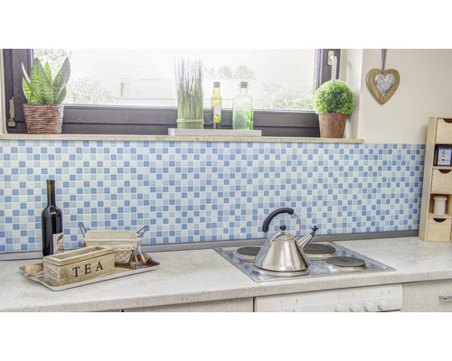 Kuchynská scéna s modrým mozaikovým pozadím, krabičkou na čaj, fľašou vína a varnou doskou