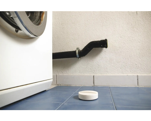 Práčka, odpadová rúra a dávkovacia pomôcka na prací prostriedok na modrej dlažbe