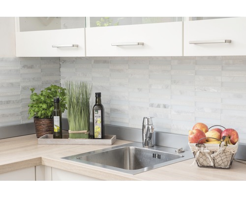 Kuchynský drez s batériou, dekoráciou a potravinami na pracovnej doske pred obkladom