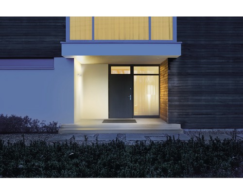 Osvetlený vchod do domu s vchodovými dverami a vonkajšími nástennými svietidlami