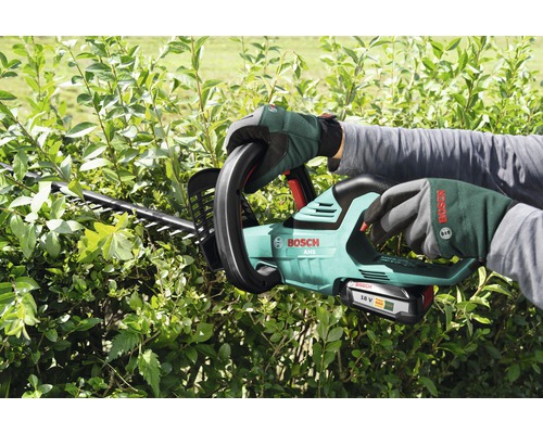 Osoba strihá živý plot pomocou akumulátorových nožníc na živý plot Bosch