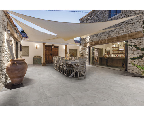 Vonkajší priestor s dlažbou, dlhým stolom, stoličkami a slnečnou plachtou