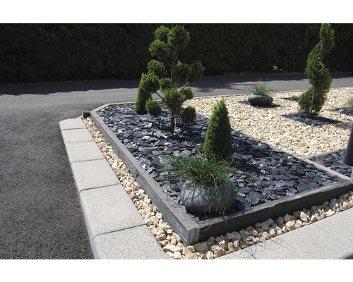 Upravená záhrada s rastlinami, kameňmi a obrubníkmi trávnika